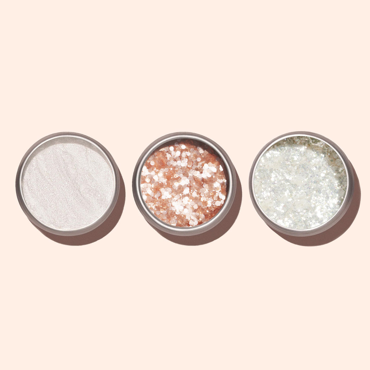 Trois contenants ronds de Pearlescent Glitter Flakes Manucurist vus de dessus : l’un avec une poudre blanche lisse, l’un rose avec de grosses paillettes nacrées, et l’un argenté avec des paillettes fines — le tout sur un fond beige pour une manucure éclatante.