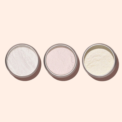 Trois petits pots ronds de Poudre Effet Glazed Blanc Manucurist, dévoilant des reflets blanc, rose et jaune pâle pour une manucure nacrée, soigneusement alignés sur un fond beige clair.