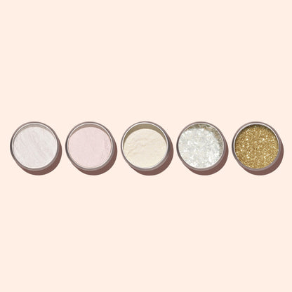 Cinq petits pots de White Glazed Effect Powder Manucurist alignés, chacun contenant une poudre ou des paillettes uniques pour des accents nacrés ou un effet ongles blancs glacés, sur un fond beige clair.