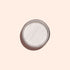 La poudre White Glazed Effect Powder de Manucurist, une poudre blanche scintillante très fine dans un petit boîtier métallique rond, est présentée sur un fond beige clair avec une ombre douce sur la gauche — idéale pour créer des looks glazed.