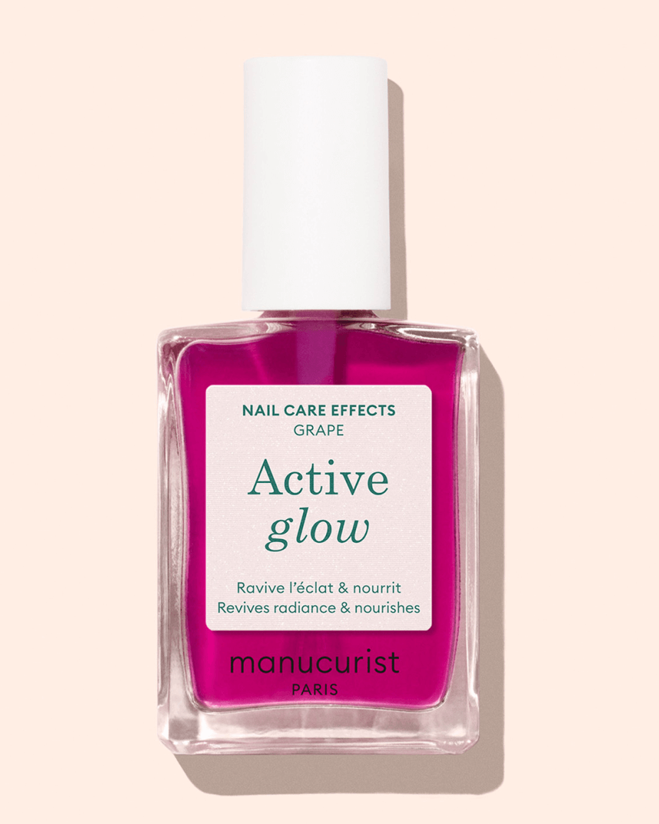 A bottle of Manucurist Paris Active Glow nail polish with bright pink liquid, featuring a white label with green text on a light beige background.