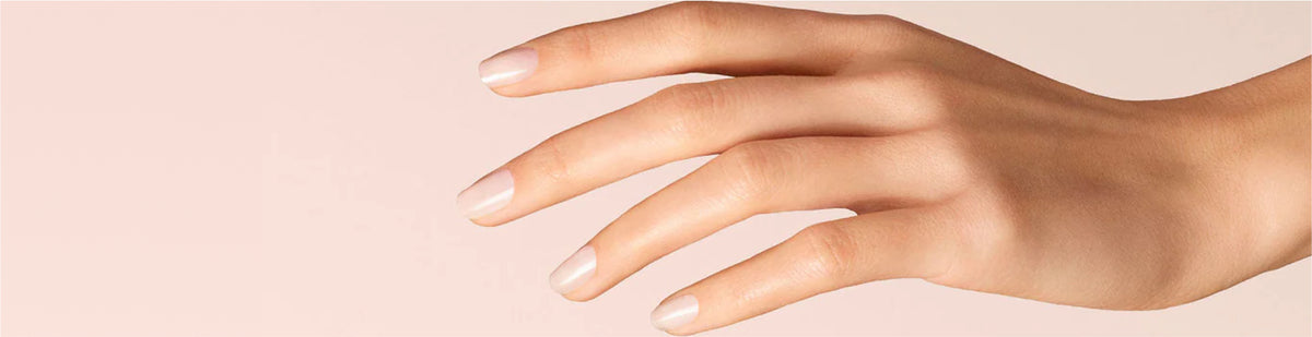 A close-up of a hand with well-groomed fingernails and smooth skin, positioned against a light peach background.