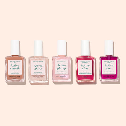 Five bottles of Manucurist nail care polish are arranged in a row against a light beige background. Each bottle, part of Manucurist’s innovative Active™ collection, is labeled with a different effect: Active™ Smooth 02, Active Shine, Active Plump, and two bottles of Active Glow. These CC Polish formulas by Manucurist offer targeted solutions for healthy-looking nails.