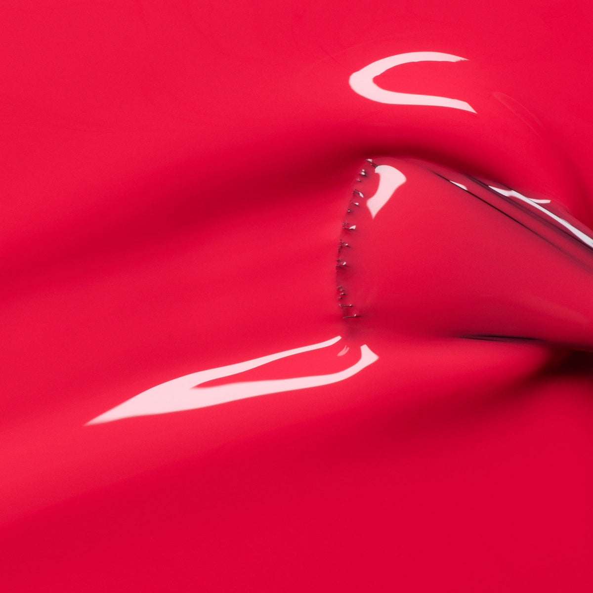 A shiny, stretchy pink-red surface—reminiscent of Manucurist&