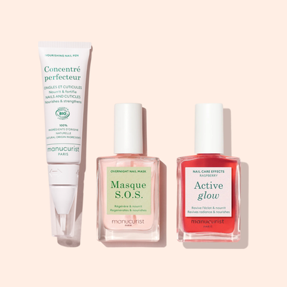 The Manucurist Nourishing Nail Pen - Cosmos Organic is featured on a light pink background alongside other manicure essentials.