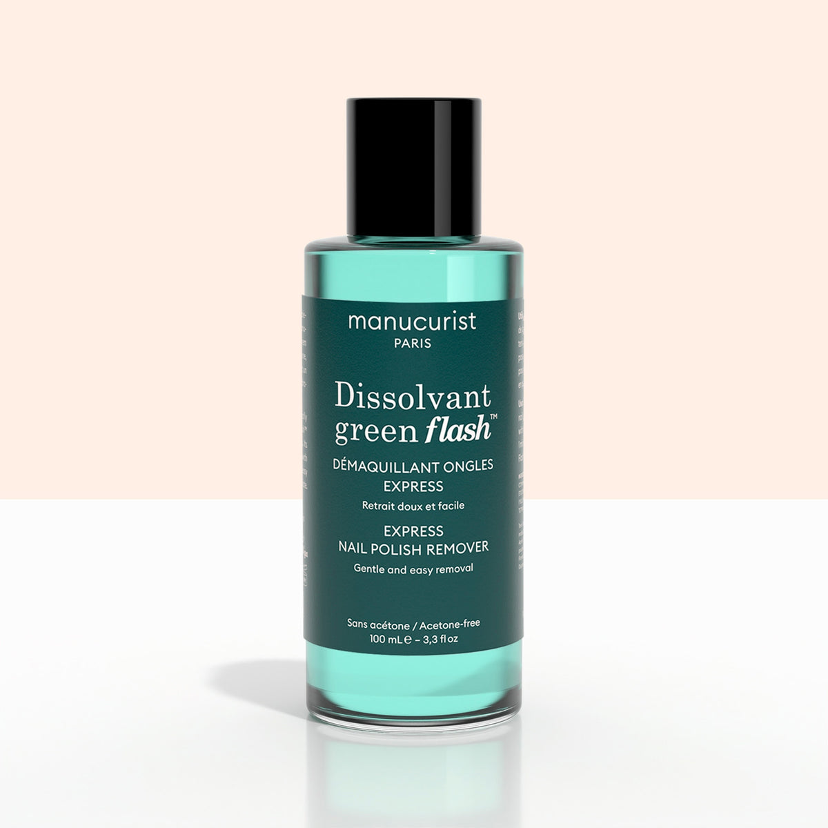 A green bottle of + Green Flash™ Gel Polish Remover by Manucurist-test, gentle and acetone-free with 99.4% bio-sourced ingredients, stands on a pale surface against a light background.