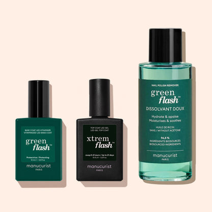 Three Manucurist products are side by side: a Vitaminized Base Coat Green Flash™, a black xtrem flash top coat, and a tall bottle of Green Flash gentle nail polish remover.