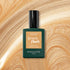 A bottle of Manucurist’s Gold Sand gel nail polish rests on a gold sand background, its label featuring instant dry and extra long wear benefits with an iridescent shine.