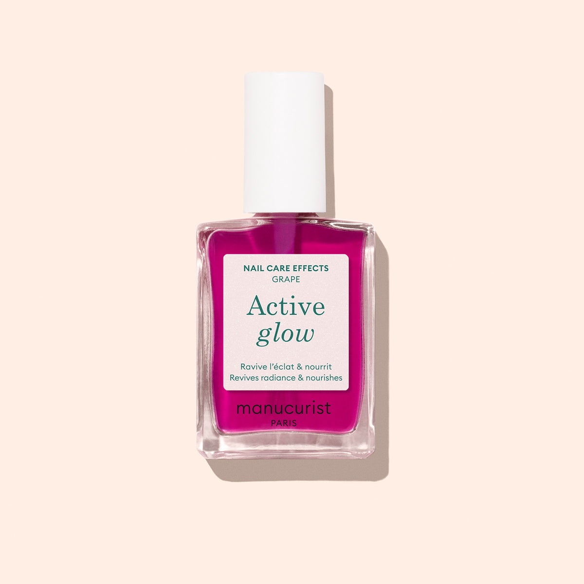 Un flacon de soin pour les ongles Active™ Glow Grape de Manucurist, avec un bouchon blanc et un liquide rose, conçu pour sublimer votre brillance naturelle, présenté sur un fond beige clair.