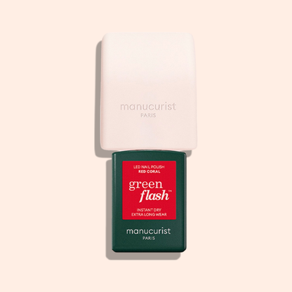 A rectangular green Mani Helper bottle labeled green flash™ and a white square LED lamp, both by Manucurist US, are set on a pale pink background—perfect for flawless manicures and nail polish application.