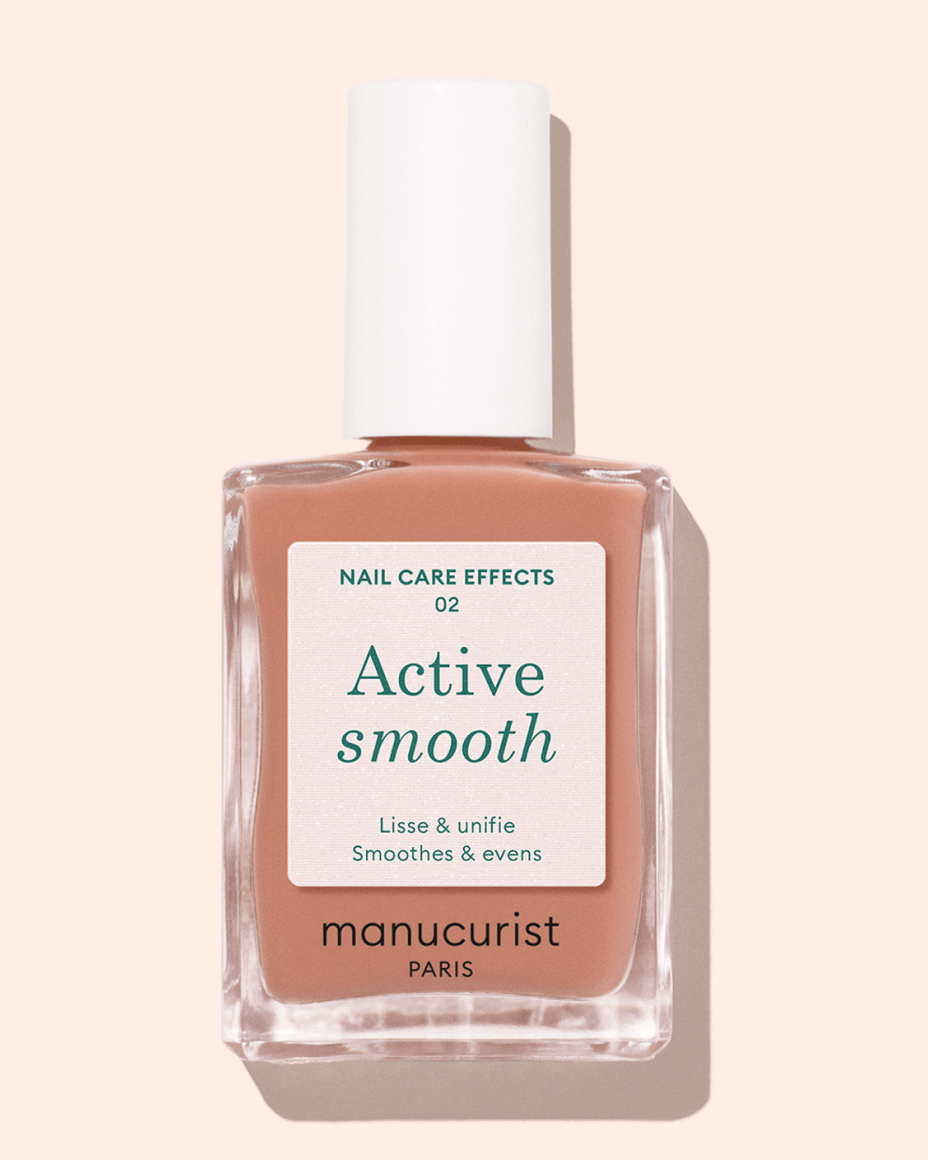A bottle of Manucurist Paris nail polish labeled Active Smooth. The label describes it as smoothing and evening for nails. The polish is a light nude shade, with a white cap and a minimalist design.