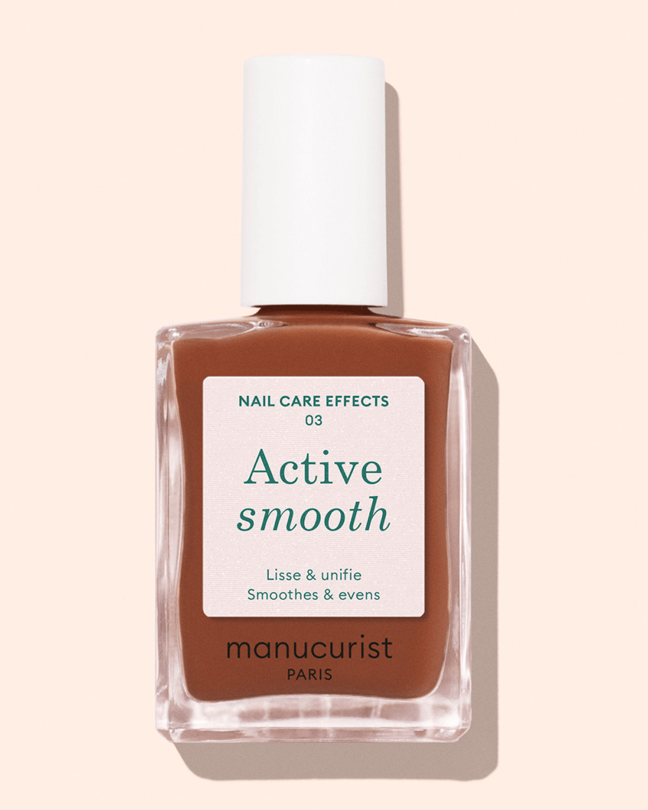 A bottle of Manucurist Paris Active Smooth nail polish with a white cap, filled with a brownish shade, labeled Active smooth and described as smoothes  evens.