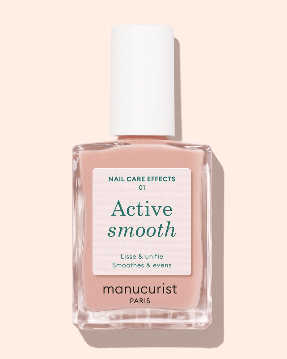 A bottle of Manucurist Paris nail polish labeled Active Smooth with a white cap, shown against a light beige background. The label mentions it smoothes and evens nails.