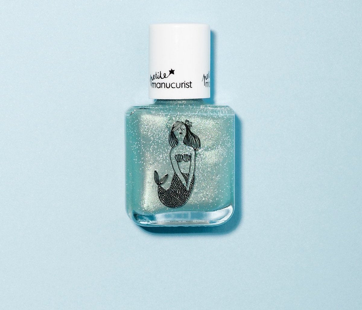 Un flacon de vernis à ongles transparent avec un bouchon blanc, orné d'une illustration de sirène pailletée sur le devant, sur fond bleu clair.