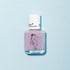 Un flacon de vernis à ongles pour enfants Manucurist Janis the Seahorse violet clair avec un bouchon blanc, orné d’une illustration d’hippocampe noir couronné. Formulé à partir d’ingrédients d’origine naturelle et présenté sur un fond bleu clair.