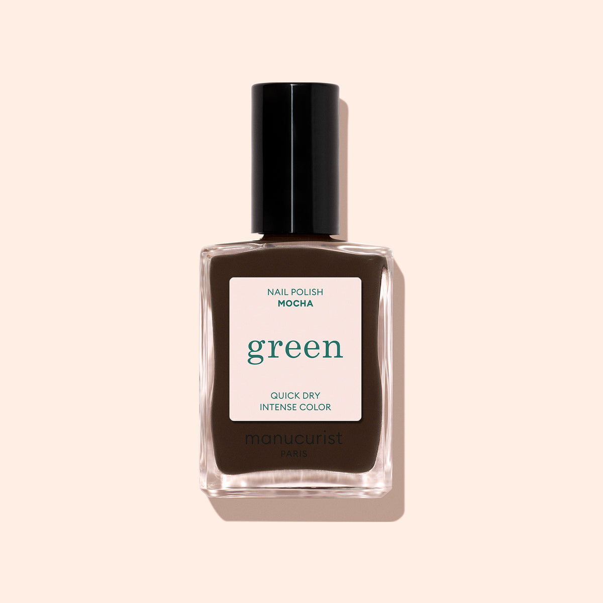 A bottle of Manucurist Mocha, a dark brown nail polish with cool undertones and a black cap labeled “green,” is shown against a pale beige background.