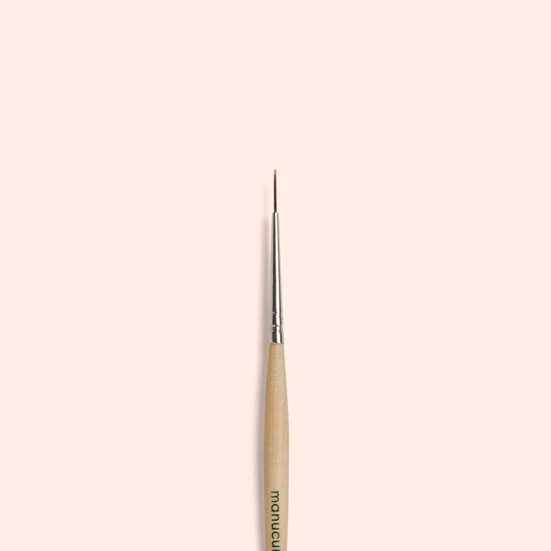 The Manucurist Liner Brush, featuring vegan synthetic bristles and a fine tip, is vertically centered on a simple light beige background.
