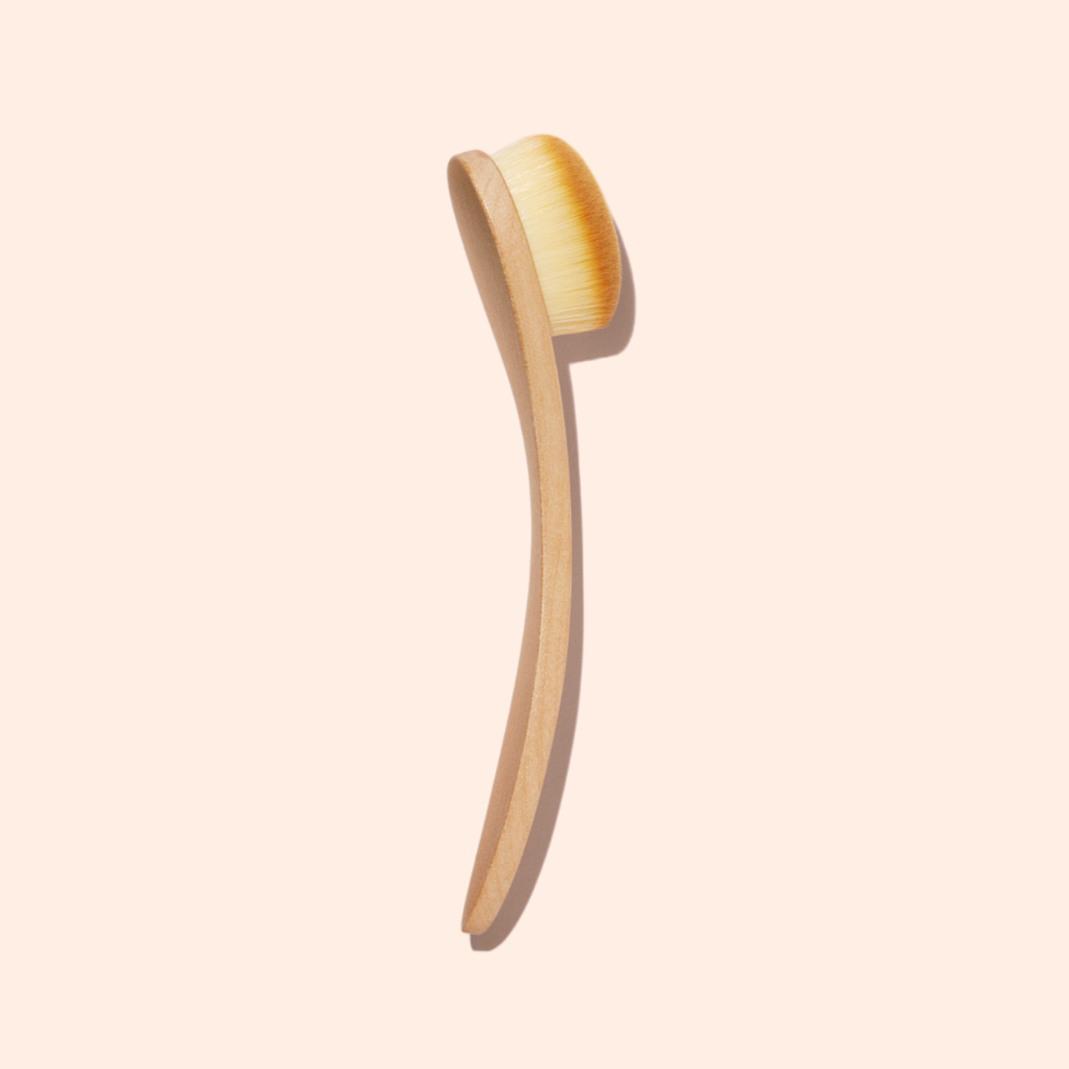 The Manucurist Dust Brush features a wooden body, long curved handle, and soft vegan bristles, shown against a light beige background.