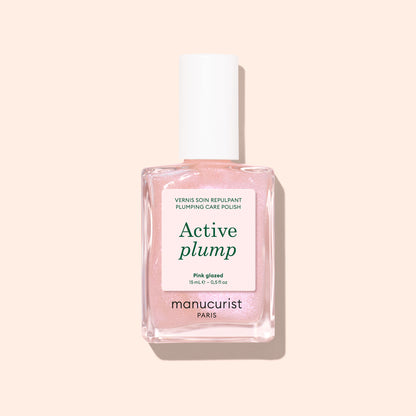 Un flacon de vernis à ongles au collagène Manucurist Active™ Plump Pink Glazed, dans une teinte rose clair, avec un capuchon blanc et présenté sur un fond pêche pâle — idéal pour des ongles hydratés et un soin des ongles doux à base de plantes.