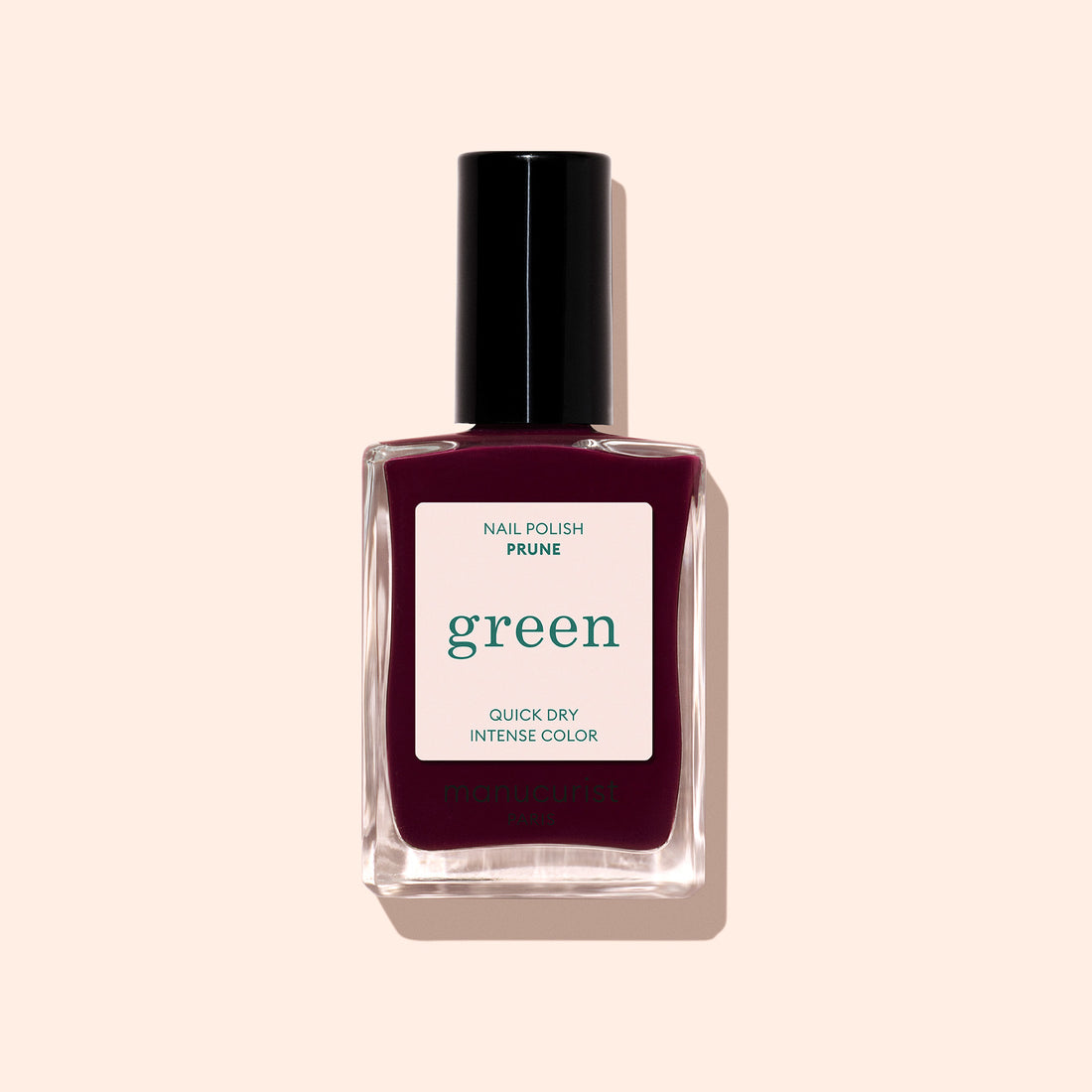 Un flacon de Prune de Manucurist, un vernis à ongles vintage à étiquette verte couleur prune profonde, au séchage rapide et à la couleur intense, présenté sur un fond beige pâle.