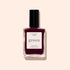 Un flacon de Prune de Manucurist, un vernis à ongles vintage à étiquette verte couleur prune profonde, au séchage rapide et à la couleur intense, présenté sur un fond beige pâle.
