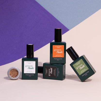 Four bottles of Pumpkin Patch gel polish by Manucurist are arranged with a small open pot of copper glitter, all set against a geometric purple, blue, and cream background.