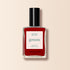 A bottle of Manucurist Red Velvet nail polish from the Green range, with a black cap and white "green" label, sits against a light beige background.