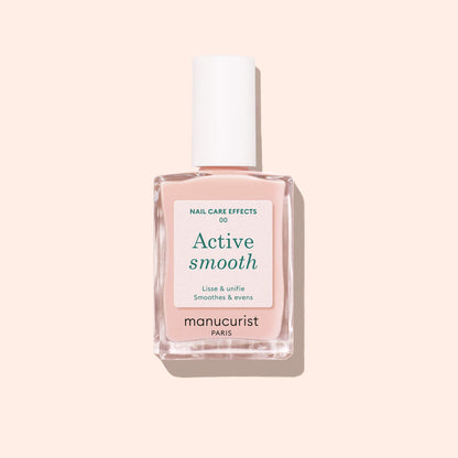 A bottle of Manucurist Active™ Smooth 00 nail treatment, topped with a white cap, sits on a light pink background. The white label features green and black text, highlighting the brand’s dedication to plant-based nails.