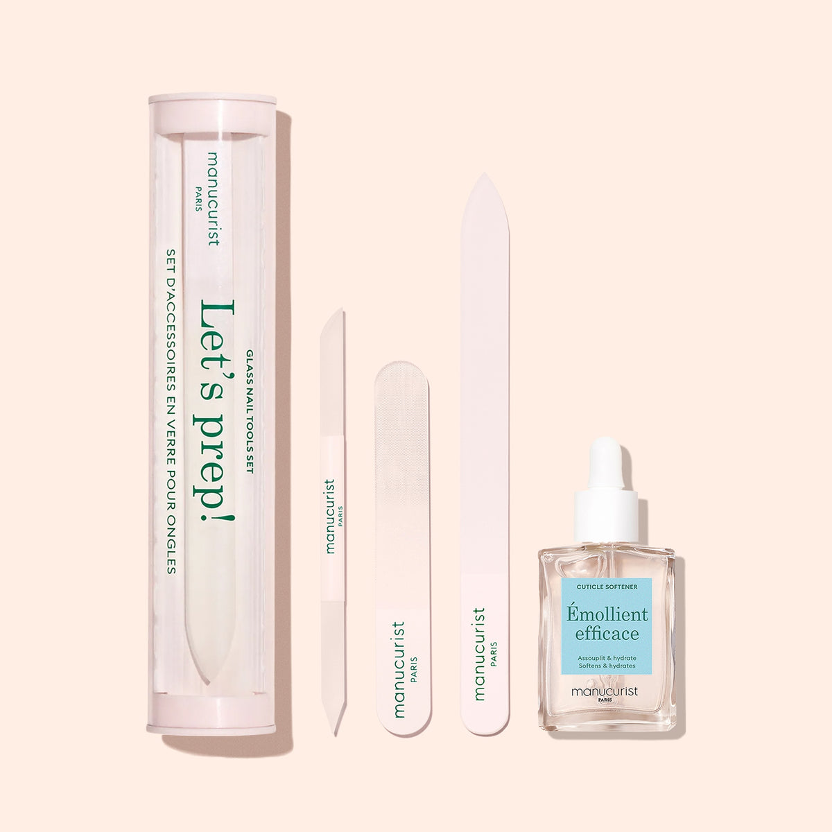 The Manucurist Glass Cuticle Pusher is shown with a “Let’s prep!” tube, three assorted nail files, and manicure oil with a dropper, all neatly arranged on a pale pink background.