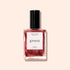 A 15 mL bottle of Manucurist Green™ nail polish in the shade Utopia, featuring a shimmery metallic crimson hue, is set against a light beige background. The label displays "Utopia" and product details.