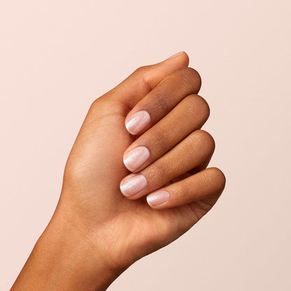 A hand with medium brown skin is shown against a light beige background. The nails are neatly trimmed and painted with Manucurist&