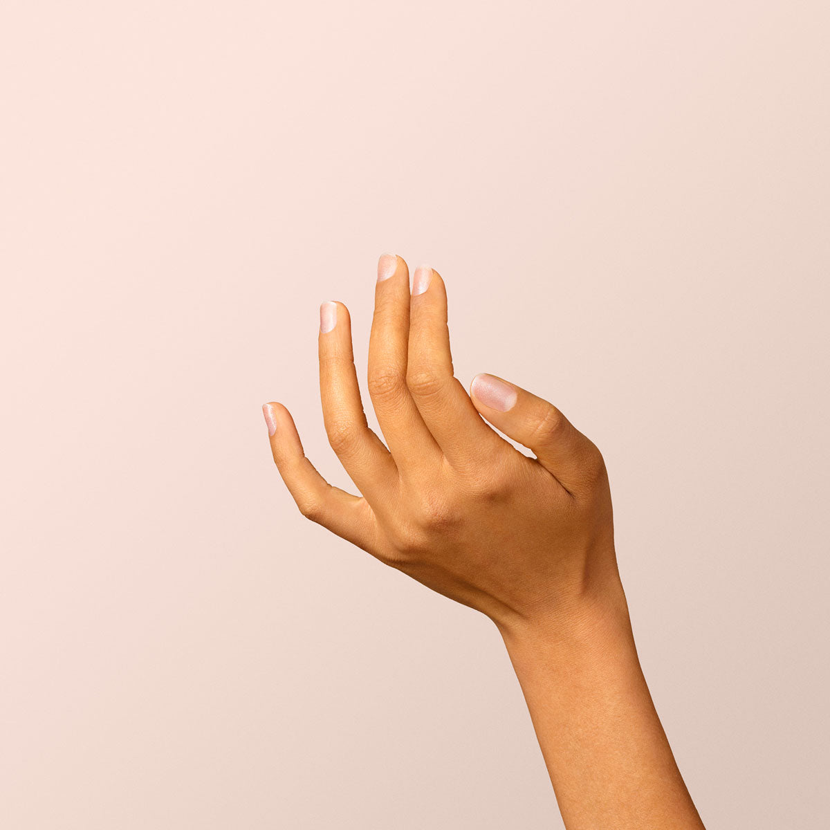A hand with light brown skin and neatly trimmed nails painted with Manucurist&
