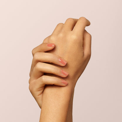 A close-up of two hands, one gently holding the wrist of the other. The nails are neatly manicured and painted with Manucurist&