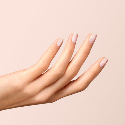 A hand with light skin tone and neatly manicured nails painted in Manucurist’s Diamant, a soft silver shade, is shown against a beige background with fingers slightly spread.