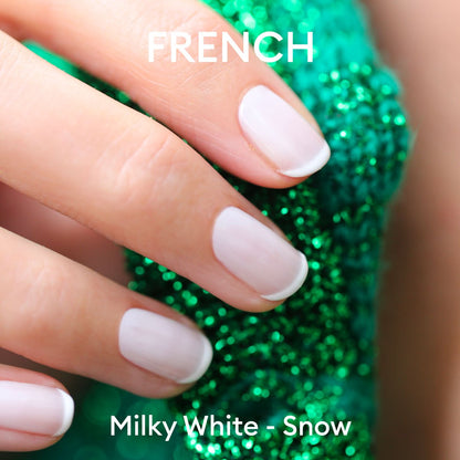 Close-up of a hand with French manicure in Manucurist Milky White gel polish, holding sparkly green textured fabric. Text on image: FRENCH at the top, Milky White - Manucurist at the bottom.