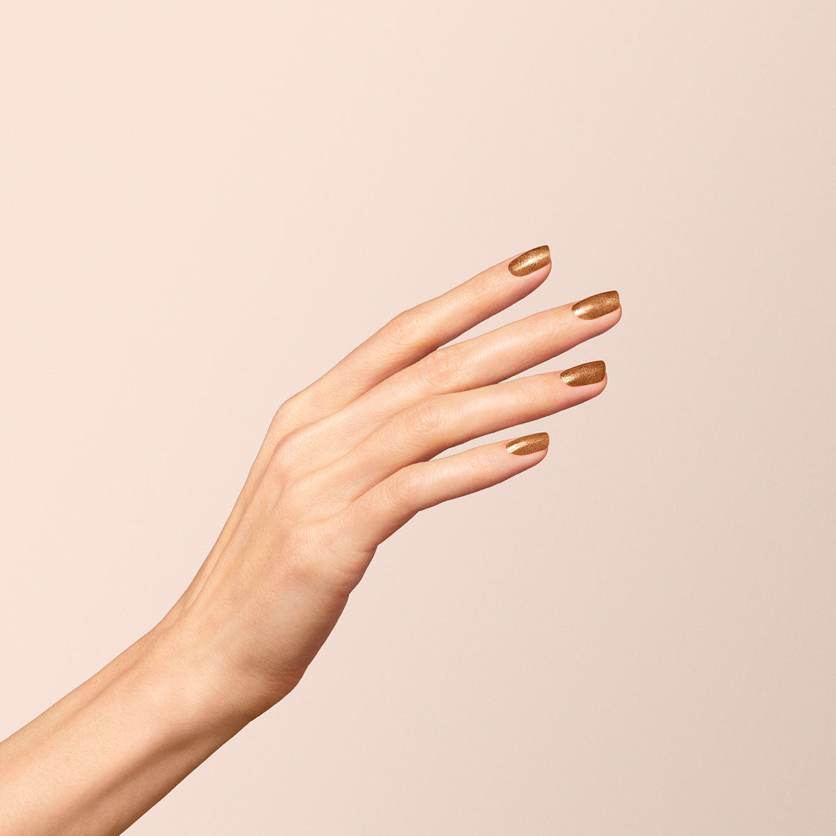 A hand with light skin is shown against a beige background, fingers gracefully extended, nails painted with Manucurist&