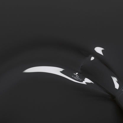 A close-up of Anthracite by Manucurist shows a black, glossy surface with smooth curves and white reflections, evoking dark grey nail polish for an abstract, minimalist effect.