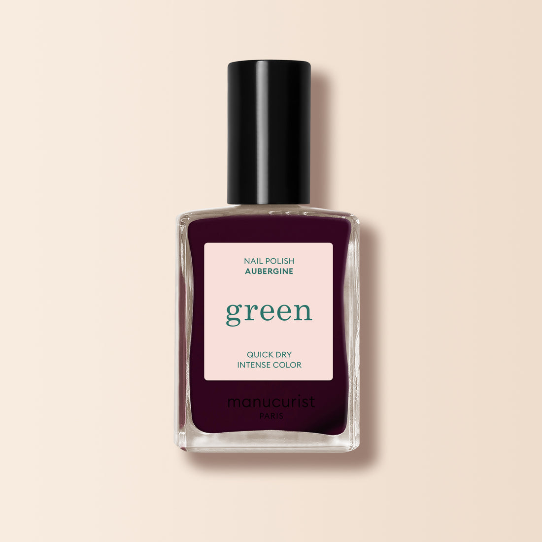 Un flacon de vernis à ongles Manucurist Aubergine, dans une teinte violet profond avec un capuchon noir, sur fond beige clair.