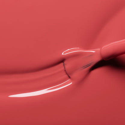 A close-up of a brush spreading Manucurist’s Bois de Rose nail polish, creating a smooth, glossy streak of rosewood pink across the surface.