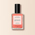 A bottle of Manucurist Bird of Paradise nail polish features a black cap and a white label with green and red text, shown on a soft beige background.