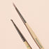 The Manucurist Dotting Tool  Nail Art Liner Brush Duo features light wooden handles and silver tips, and is shown arranged on a pale pink background.
