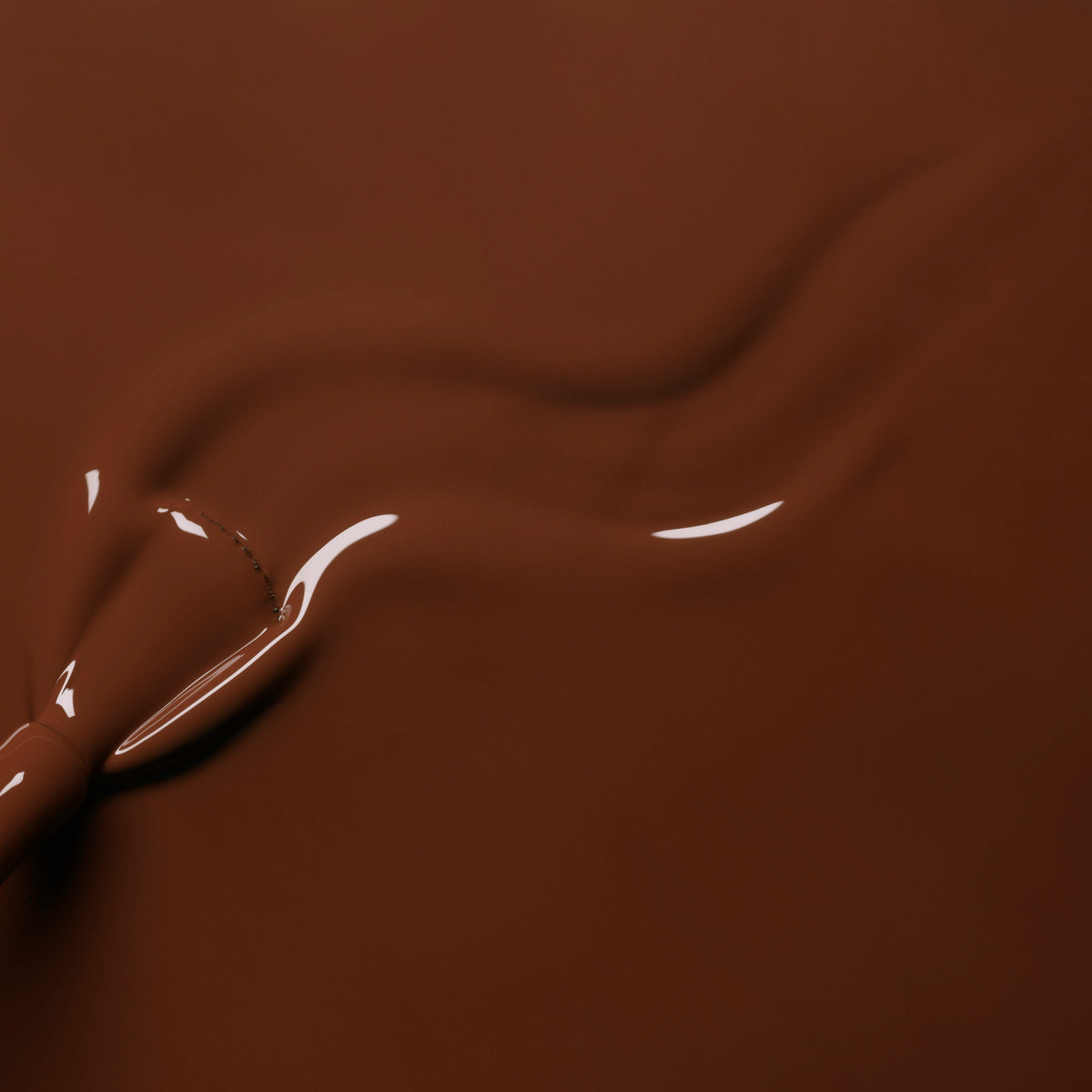 Gros plan de chocolat lisse et fondu, avec un motif brillant et tourbillonnant — rappelant le vernis gel Chestnut de Manucurist.