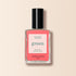 A bottle of Manucurist nail polish in the shade Capucine, coral pink from the Green range, with a black cap and "green, quick dry intense color" on the label, displayed against a soft beige background.