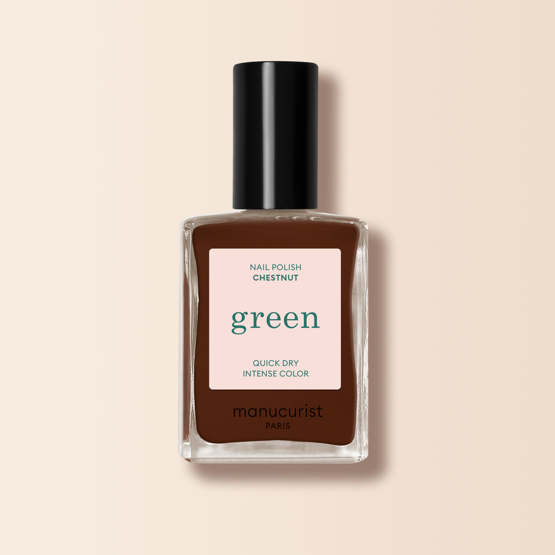 Un flacon de vernis à ongles Manucurist Chestnut posé verticalement sur un fond beige. L&