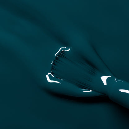Gros plan sur un pinceau appliquant le vernis à ongles Manucurist Dark Clover, montrant des touches vert canard lisses et brillantes ainsi que des reflets lumineux sur la surface fraîchement vernie.