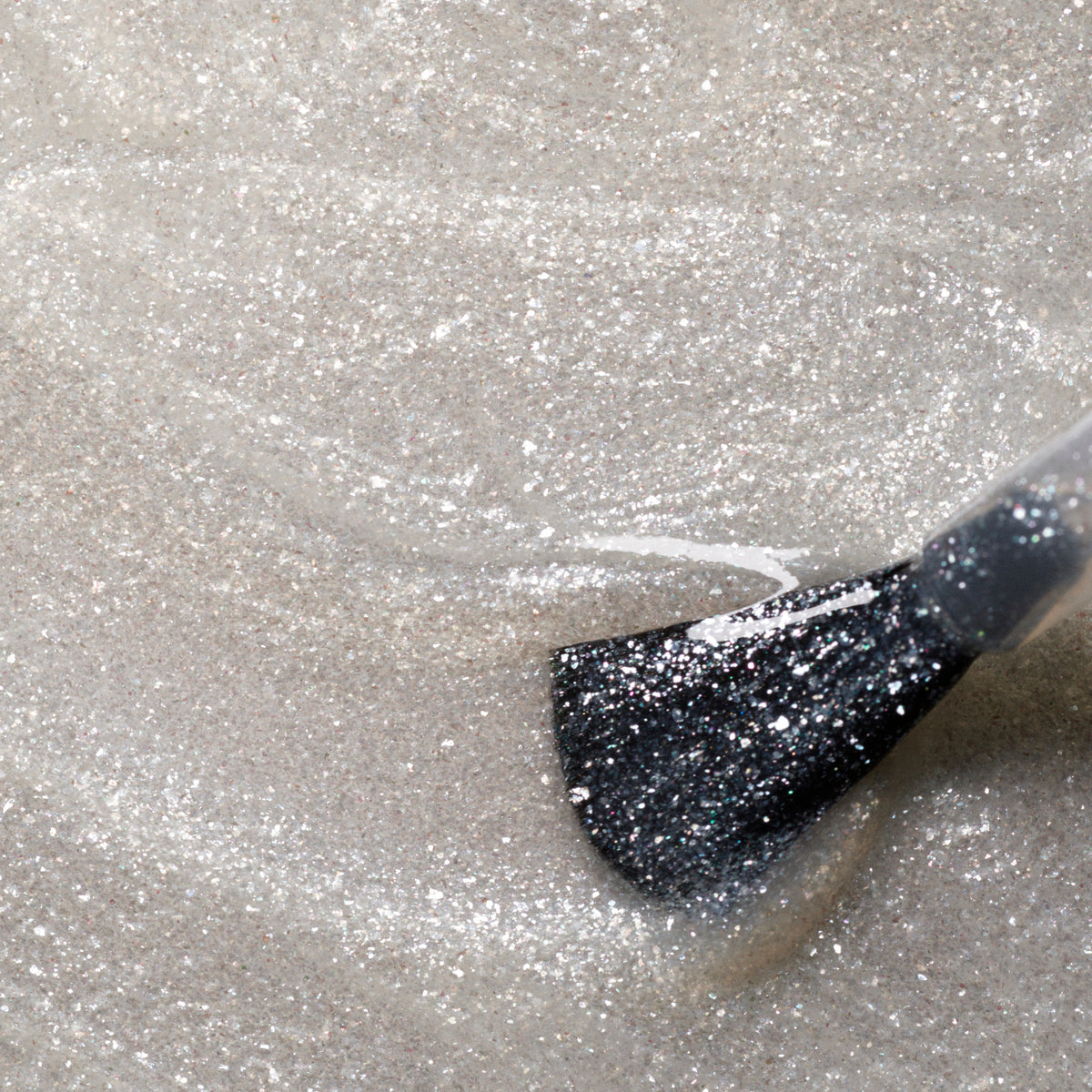 A close-up shows the Manucurist Diamant brush applying a shimmery silver gel polish to a nail, with both the brush and glittery finish clearly visible.