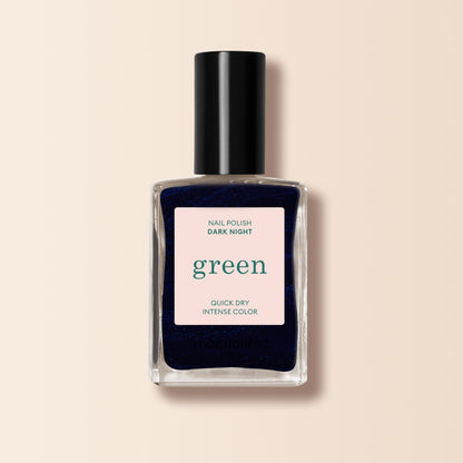 Un flacon carré en verre de vernis à ongles Manucurist Dark Night, teinte bleu nuit avec un bouchon noir. L’étiquette indique Dark Night, gamme Green™, Quick Dry Intense Color, sur fond pâle.