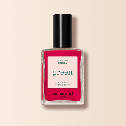A bottle of Manucurist Fuchsia nail polish, featuring a black cap and vibrant pinky purple shade, from the Green™ range, shown on a light beige background.