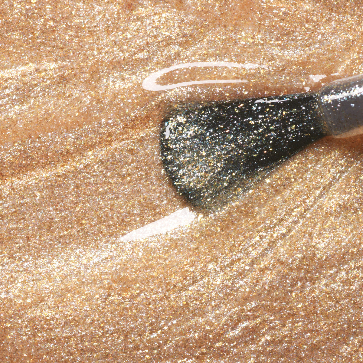 Gros plan sur un pinceau de vernis à ongles Gold Manucurist appliquant de fines paillettes dorées pour un effet scintillant et métallique de la gamme Green.