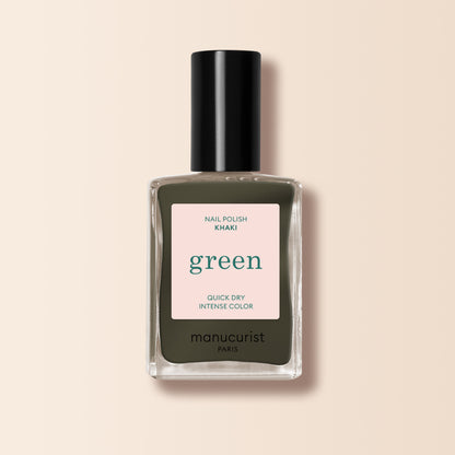 A bottle of Manucurist Khaki nail polish with a black cap, featuring quick-dry and intense color, sits on a light beige background—ideal for a modern manicure with its subtle grey undertone.